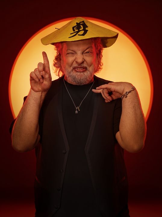 Dado con cappello giallo e ideogramma su sfondo rosso, posa comica